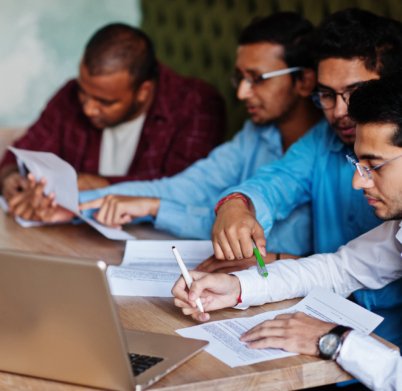 Group of four south asian men's posed at business meeting in cafe. Indians together and sign important documents. Contract to study and work.